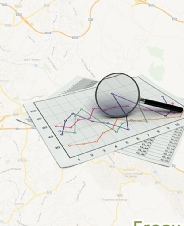 A imagem apresenta um fundo de um mapa, sobre o qual estão dispostos gráficos em papel. Um gráfico de linhas, com várias cores, é ampliado por uma lupa que está posicionada sobre ele. Ao lado, há uma caneta preta, sugerindo que se está a analisar dados. Os gráficos mostram variações de valores ao longo do tempo, com eixos claramente marcados. A parte inferior da imagem contém a palavra 'Frequência', indicando que os dados podem estar relacionados a medições ou estatísticas.
